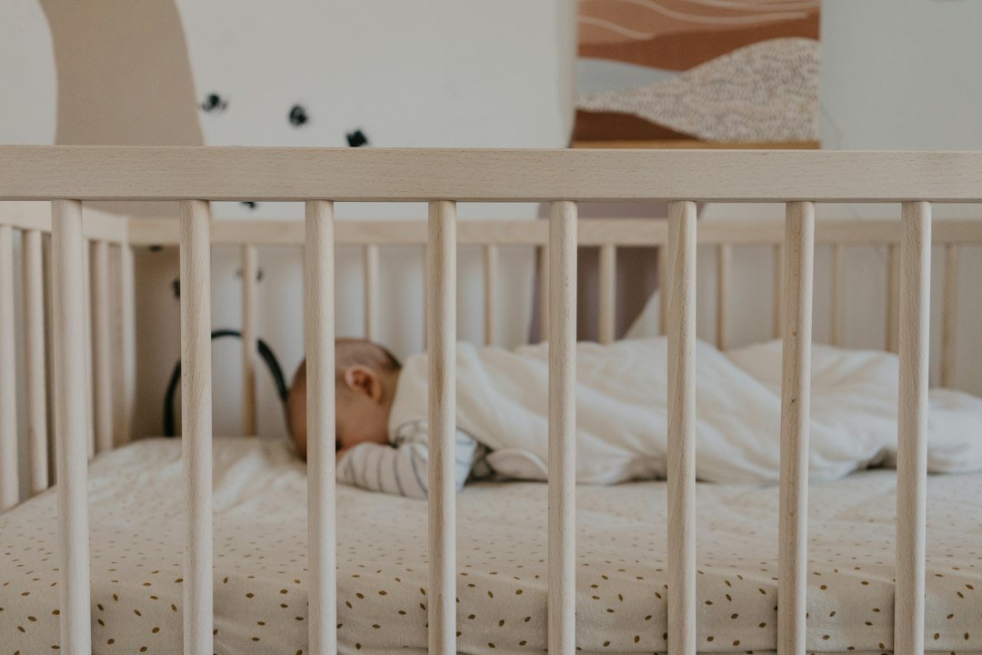 Recém-nascido dormindo de barriga para cima em um berço claro, sem objetos soltos