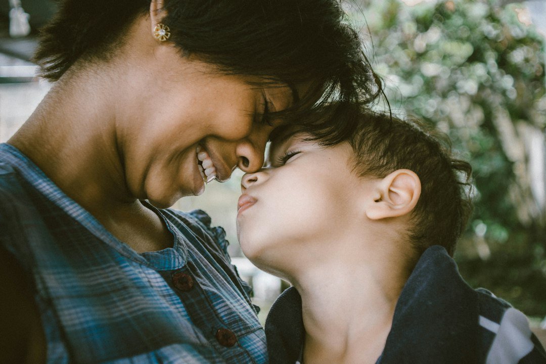 Mãe e criança pequena encostando os rostos em um momento de calma e acolhimento